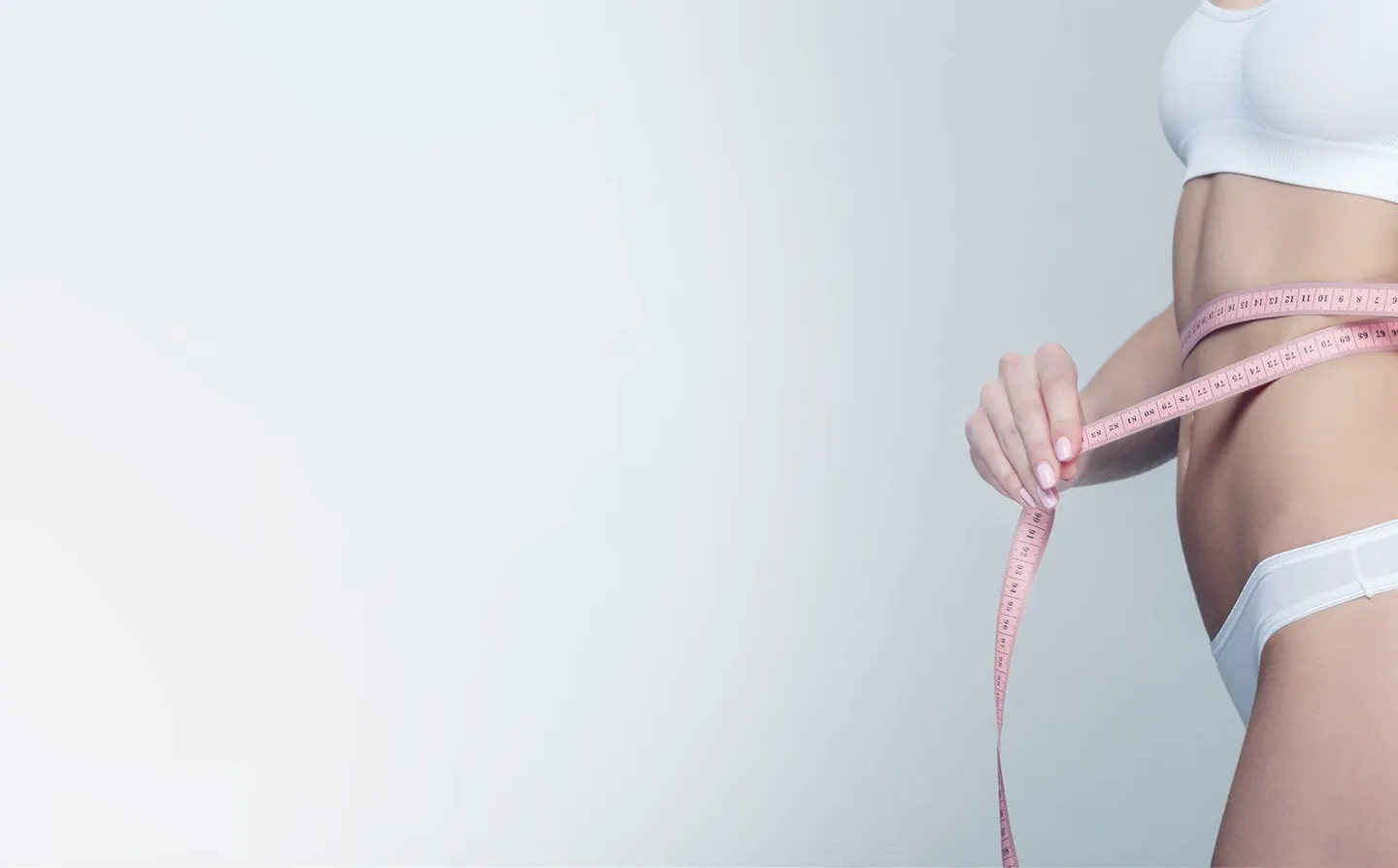 Woman measuring her waist with a tape measure